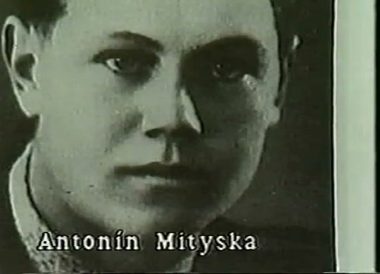 A period portrait of a young fair haired man in a dark jacket, the name Antonin Mityska captioned across the foot of the picture