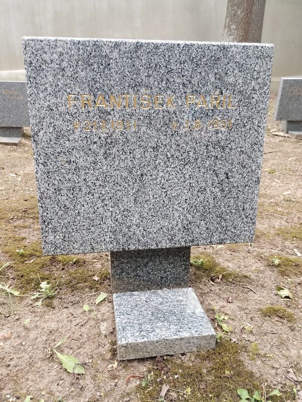 A small granite marker set in bare earth at the Dablice cemetery in Prague, cut in gold letters with the name Frantisek Paril and the dates 21 January 1911 and 3 August 1951, further markers behind it