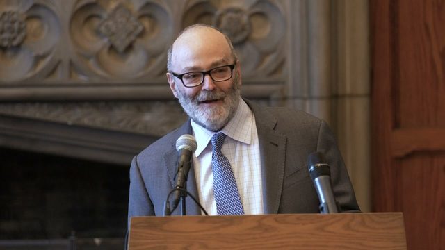 Bruce Lincoln speaking at a podium in the University of Chicago Divinity School