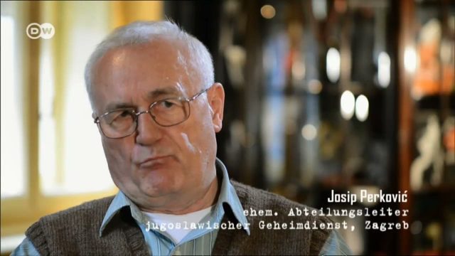 An elderly man with white hair and metal rimmed glasses in a knitted waistcoat, seated indoors and speaking to an interviewer, captioned Josip Perkovic, former department head of the Yugoslav secret service in Zagreb