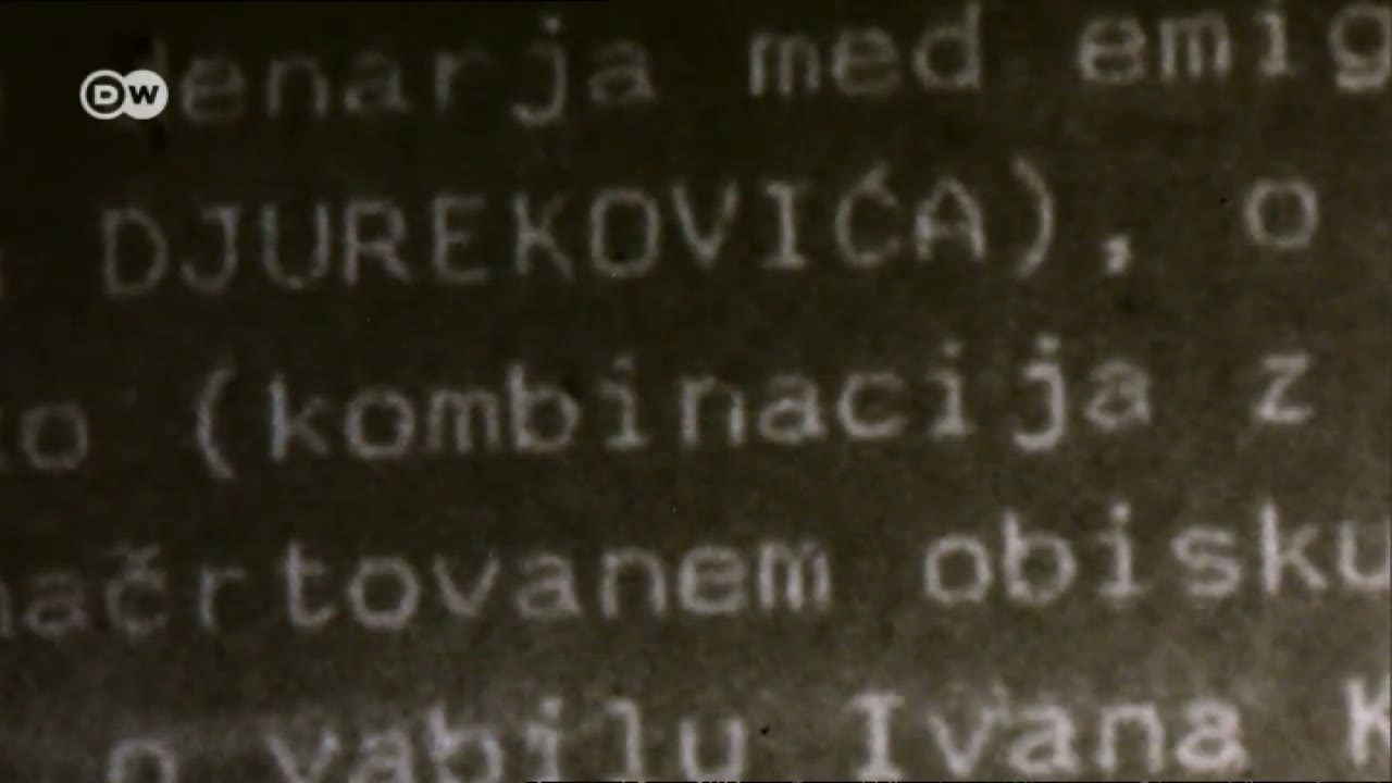 A typewritten file page photographed in extreme close up, the surname DJUREKOVICA in capitals on the second line, with Slovene wording around it about money among emigres, a planned visit and an invitation