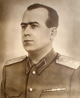 A sepia portrait of Alexandru Drăghici in uniform, stars on the collar tabs and a row of ribbons on the breast