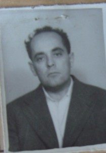 A small identity photograph of Alexandru Ioanid, dark jacket and open collar, the print curling at one corner