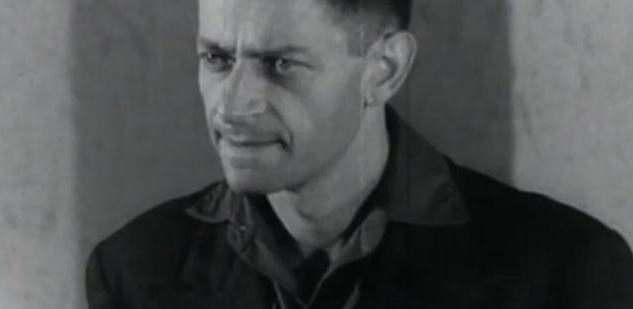 Igor Sevianu, head and shoulders, filmed in black and white against a bare plaster wall