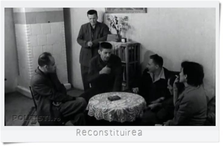Six people in a plain room around a low table with a lace cloth, one man standing behind the group, a shelf of books and a vase against the wall; the reproduction carries the Romanian caption Reconstituirea, meaning the reconstruction, and the politisti.ro watermark
