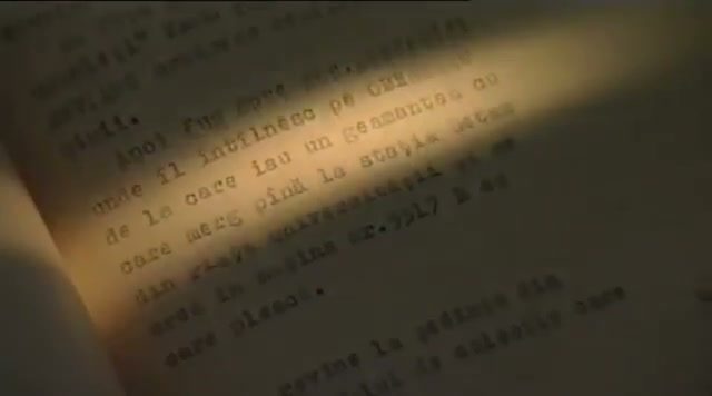 A close view of a typed page in Romanian lit by a narrow shaft of light, the lines legible in the light and lost in shadow at the edges
