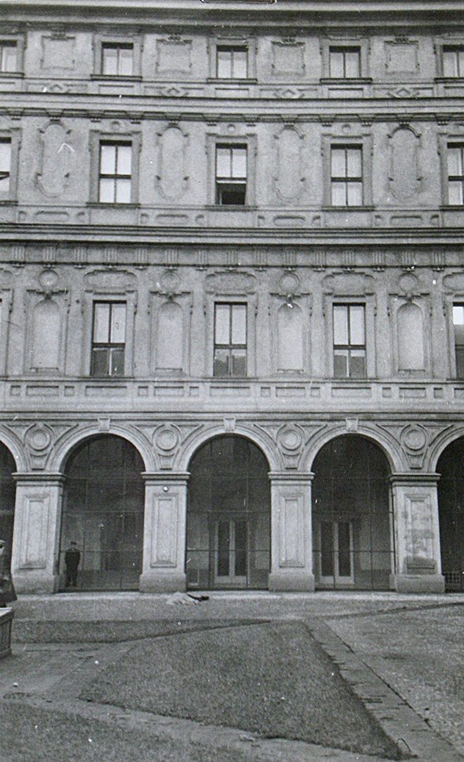 The courtyard facade of the Czernin Palace on 10 March 1948: an arcade at ground level, three rows of windows above it, one casement in the second row from the top standing open, and a small bundle on the paving at the foot of the arcade, where the body lay