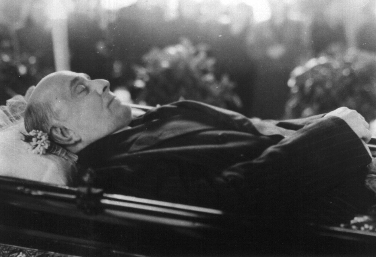 Jan Masaryk lying in state on a catafalque in the Czernin Palace, flowers and candles around the coffin