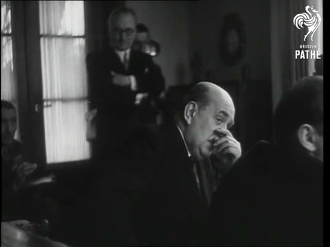 A newsreel frame from the salon of the president's villa at Sezimovo Ústí: Jan Masaryk seated in profile with his hand at his mouth, men in suits behind him