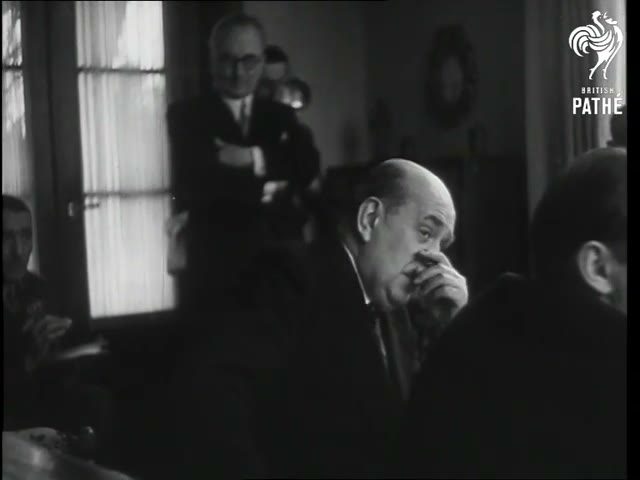 A newsreel frame from the salon of the president's villa at Sezimovo Ústí: Jan Masaryk seated in profile with his hand at his mouth, men in suits behind him