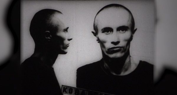 A prison identification photograph of a young man with a shaven head, shown in profile and full face, with a name board across the bottom of the frame