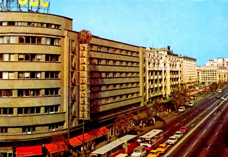 Bulevardul Nicolae Bălcescu in Bucharest in the 1970s seen from above, a department store with a vertical neon sign reading Caleidoscop, buses and cars along the boulevard