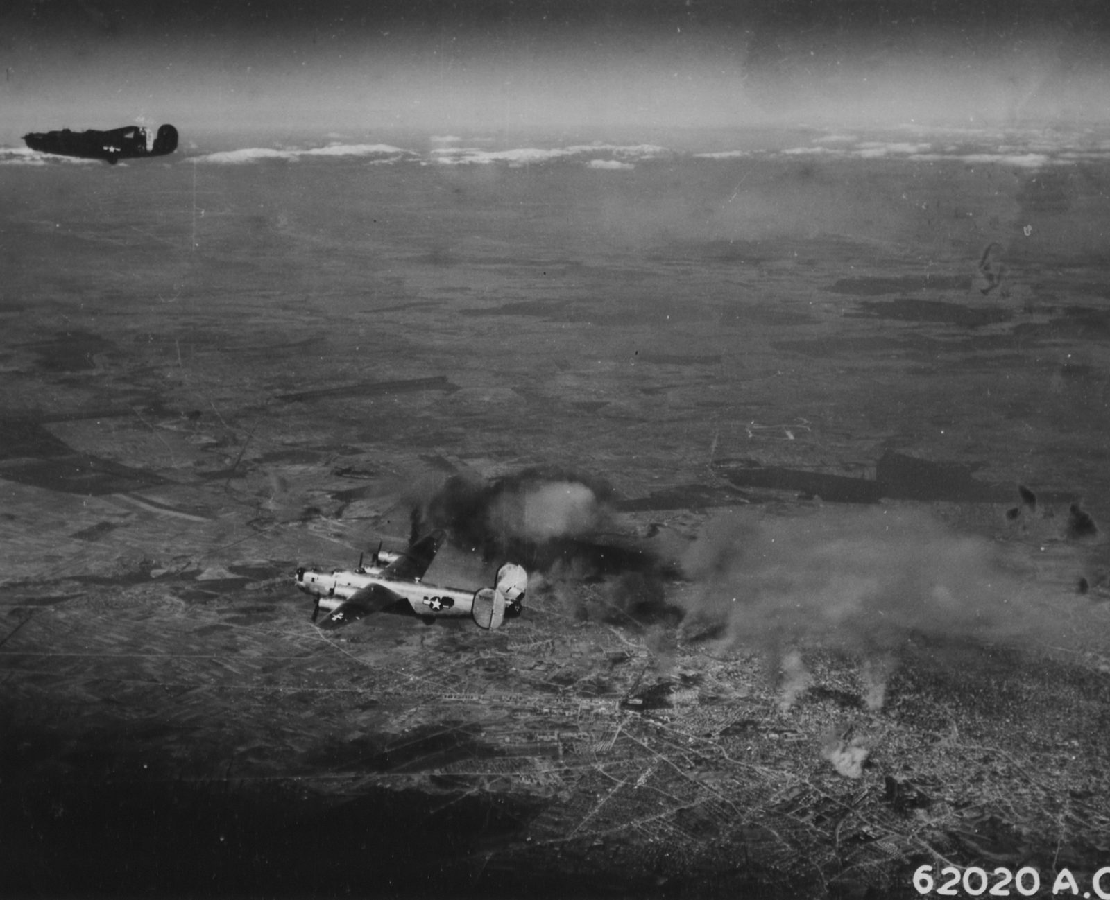 Two United States B-24 Liberator bombers over Bucharest on 4 April 1944, smoke from the bombing spreading across the city below