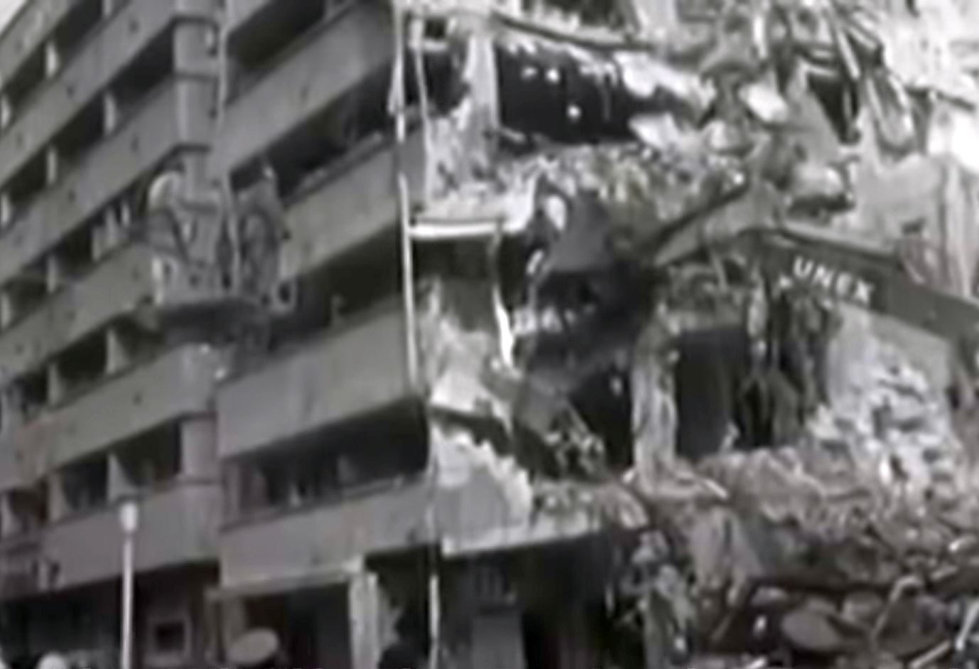 A city block in central Bucharest torn open by the 1977 earthquake: the balconies of the surviving half standing over a mound of rubble where the rest of the building came down into the street