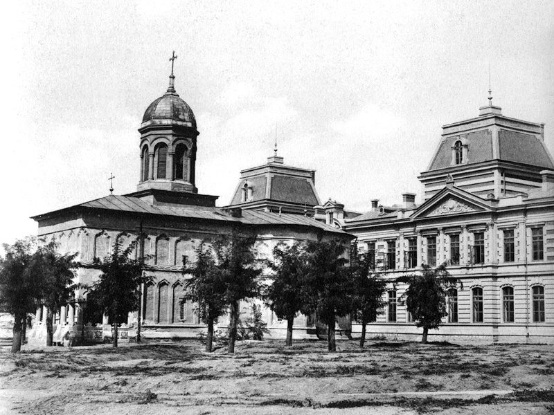 A period photograph of the Coltea church with its bell tower and, beside it, the long facade of the Coltea hospital in Bucharest, young trees along the open ground in front