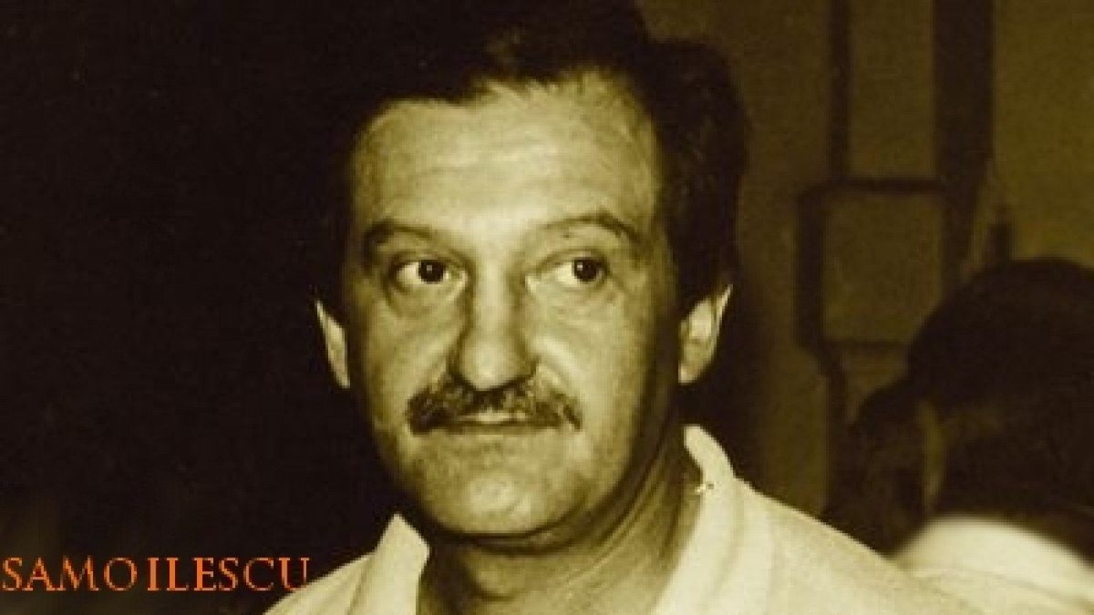 Gheorghe Samoilescu, head and shoulders, in an open collared white shirt, photographed indoors