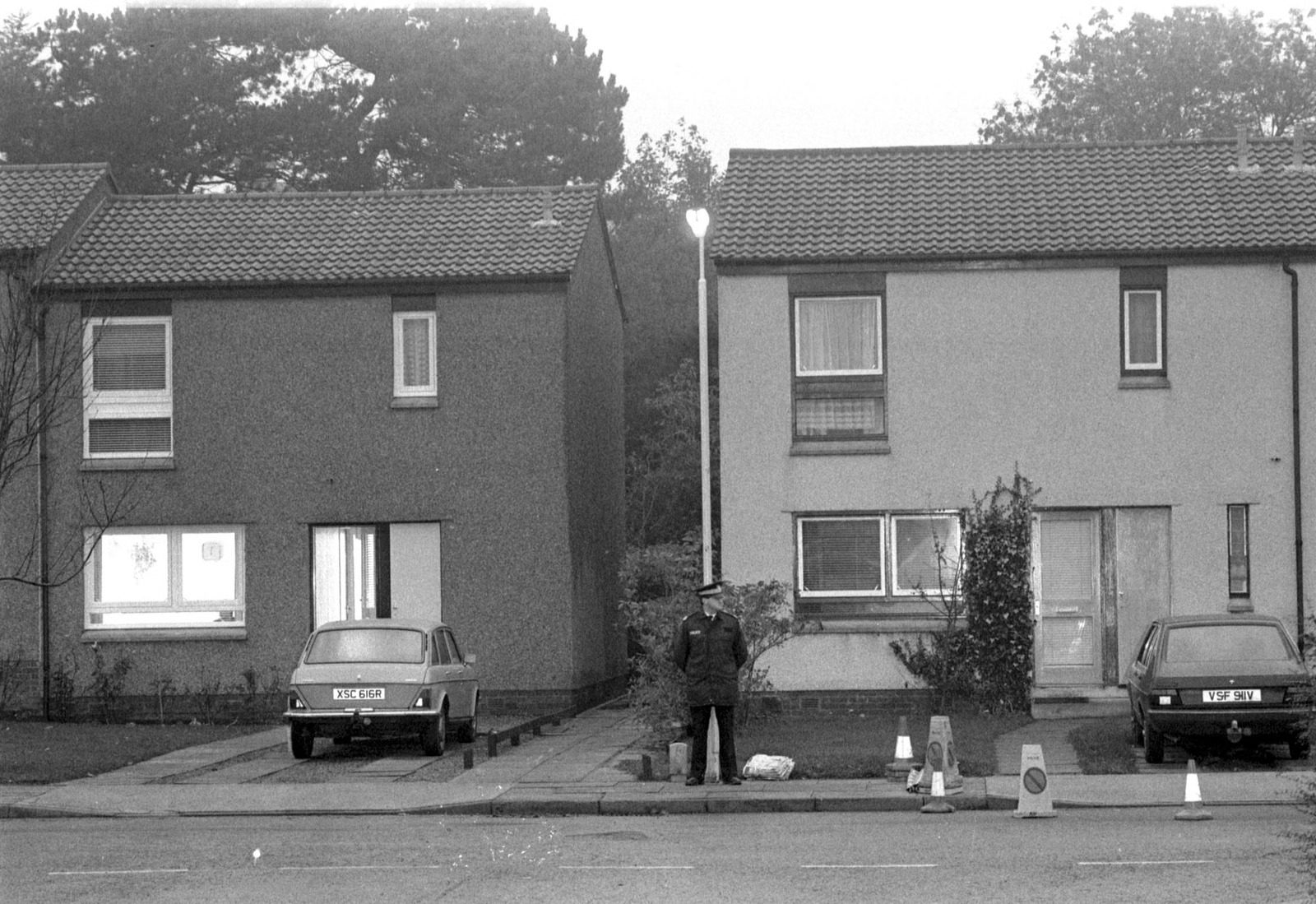 A uniformed policeman standing guard on the pavement outside a house in Kirkcaldy