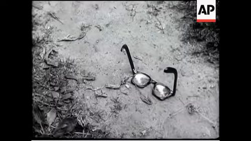 A staged newsreel frame of a pair of spectacles lying on the ground, filmed as a reconstruction for a British newsreel in July 1952