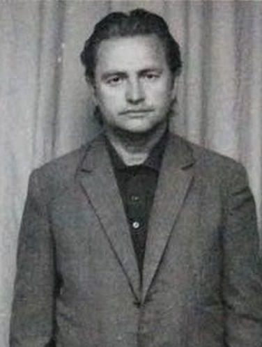 Militia identification photograph of Romulus Vereș facing the camera against a curtain, in a checked jacket with his hair swept back