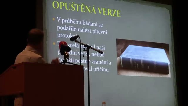A projected lecture slide with a photograph of a bound volume beside Czech bullet points saying the autopsy protocol was found, the speaker at his lectern in front of it