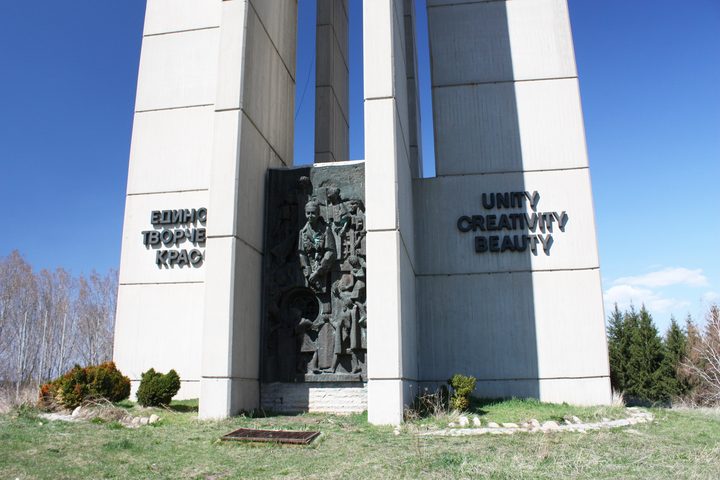 Tall white concrete pylons carrying a bronze relief of children, with the words Unity Creativity Beauty in English on one face and the same words in Bulgarian on the facing pylon