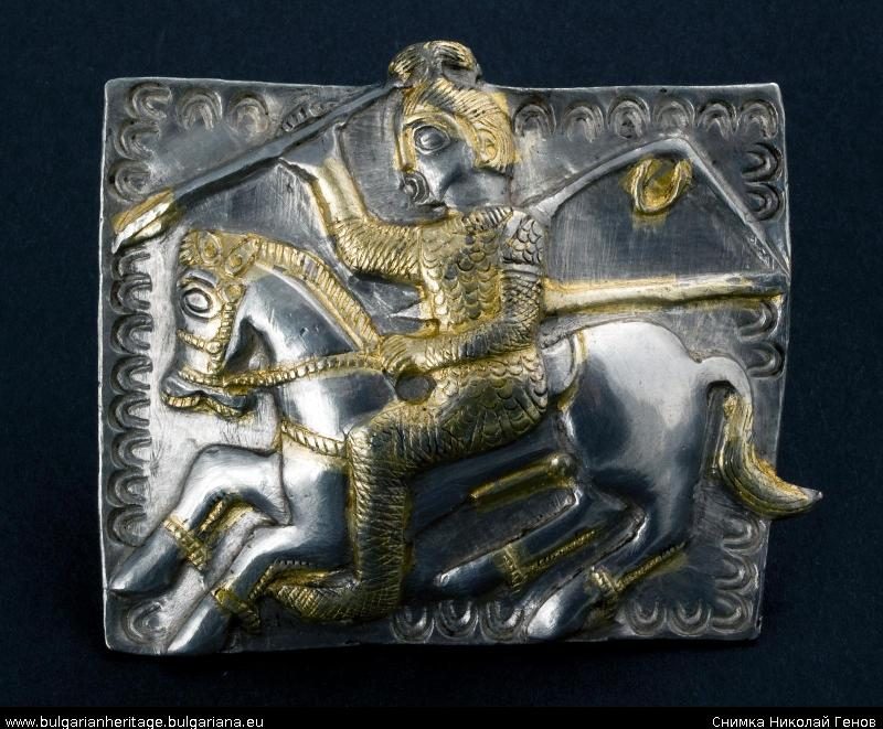 A silver harness plate worked in relief and part gilded, showing a rider with a spear on a galloping horse inside a scalloped border
